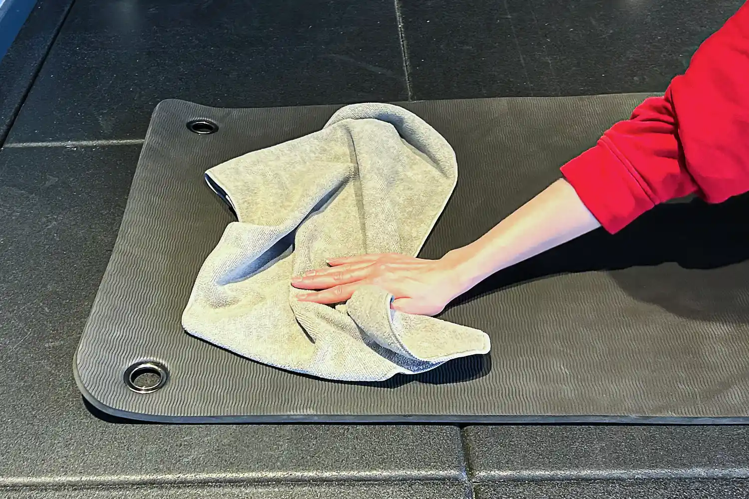 A person wipes down a yoga mat using the S&T INC. Microfiber Sweat Gym Towel