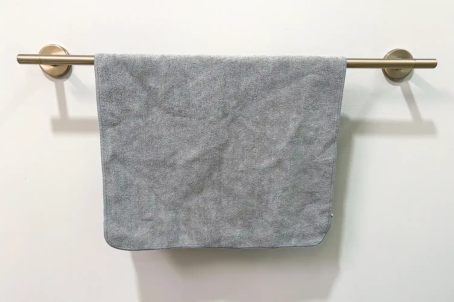 The S&T INC. Microfiber Sweat Gym Towel hangs from a towel bar
