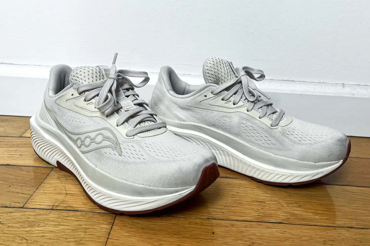 A front view of a pair of Saucony Women's Echelon 10 Running Shoes on a wooden floor