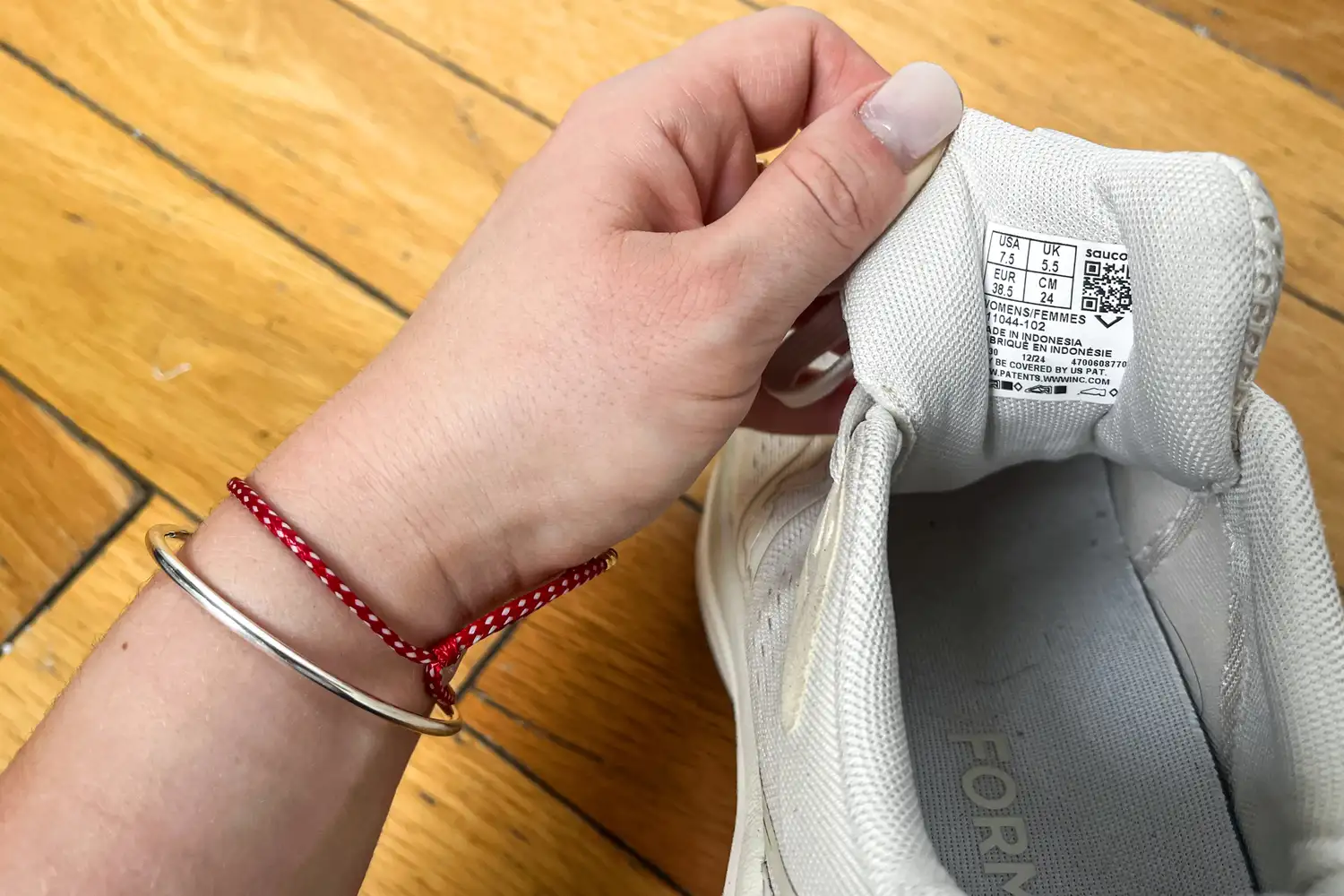 A person pulls back the tongue of the Saucony Women's Echelon 10 Running Shoes