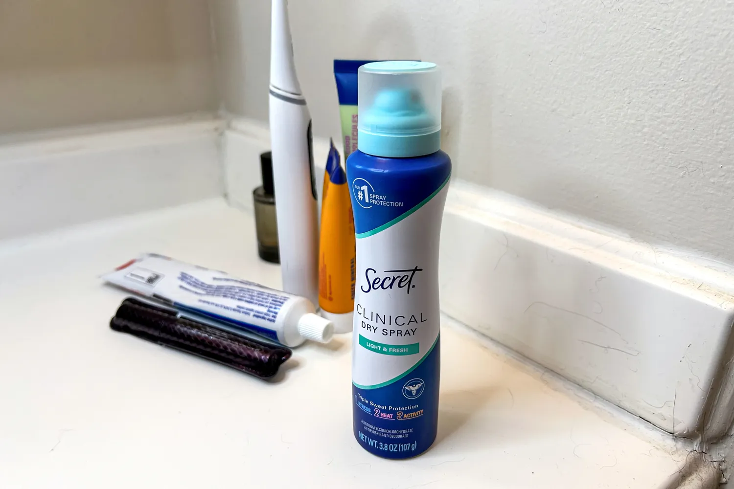 A bottle of Secret Clinical Strength Dry Spray Antiperspirant Deodorant on a bathroom countertop
