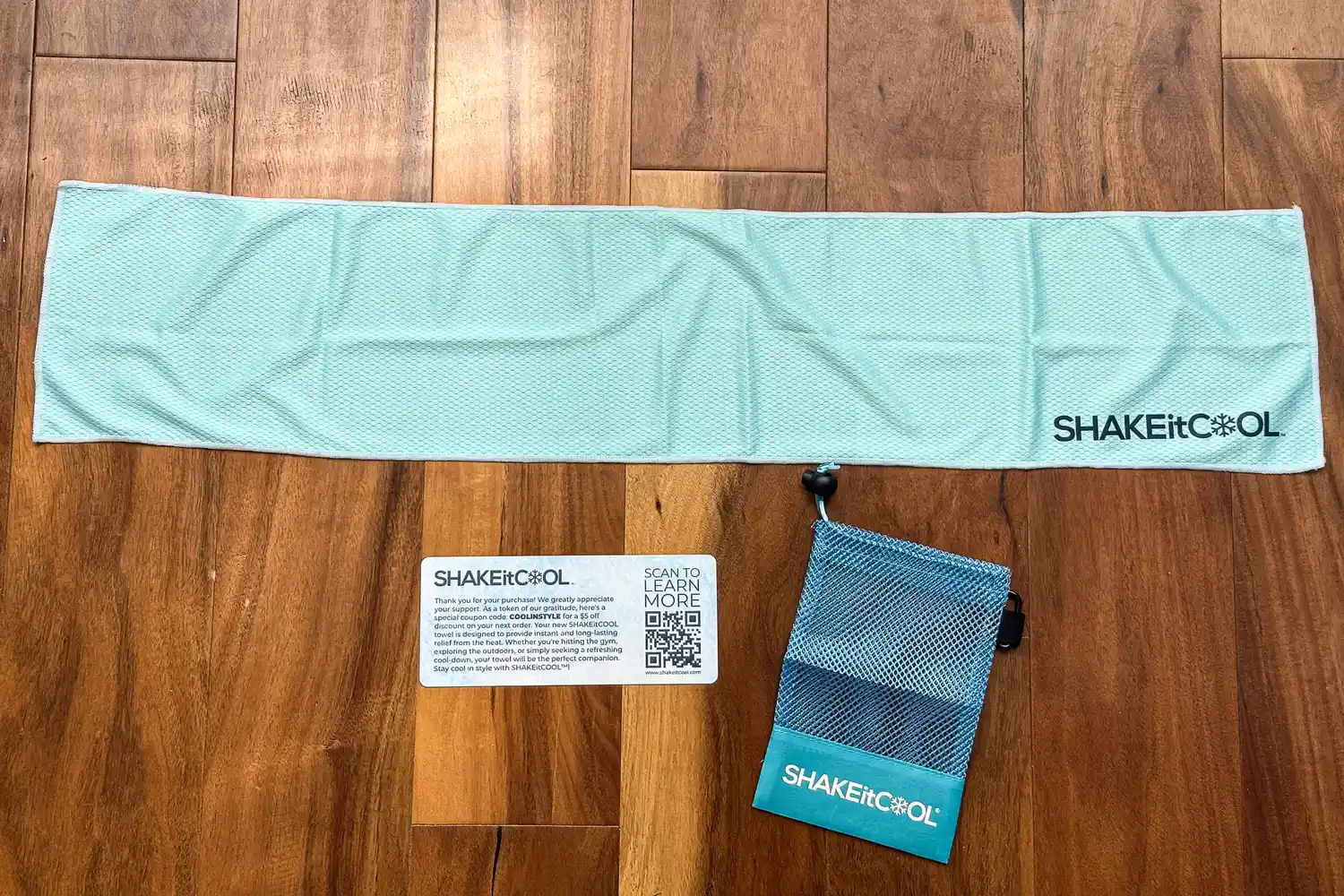 The SHAKEitCOOL Original Cooling Towel folded next to a storage bag