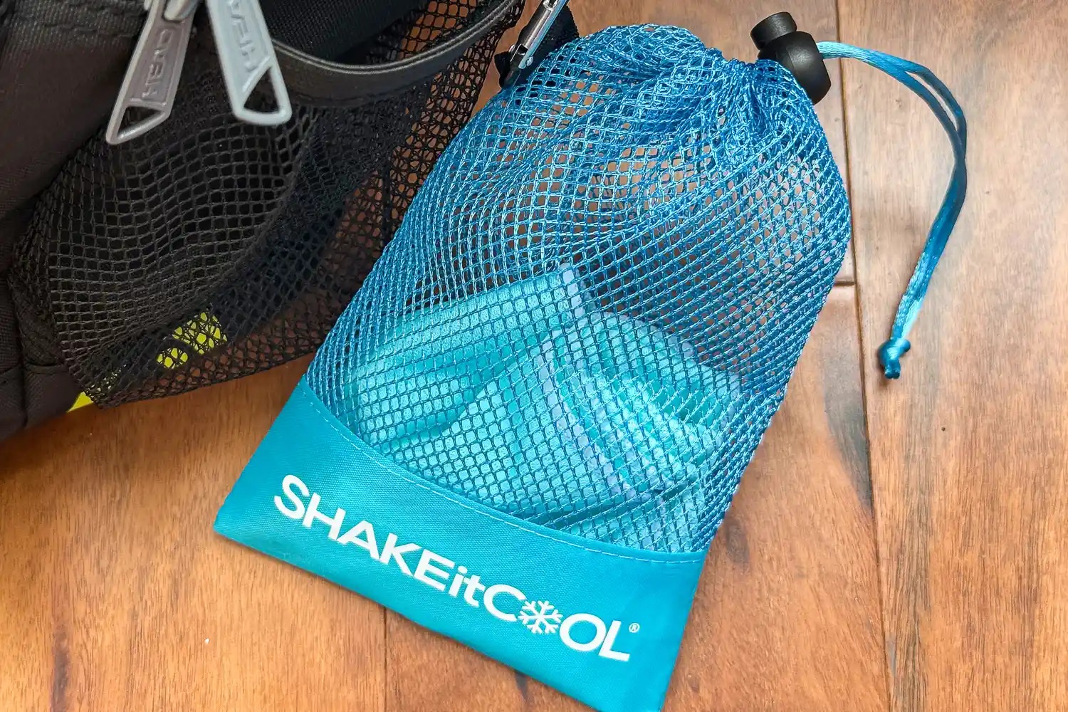 The SHAKEitCOOL Original Cooling Towel in a mesh storage bag