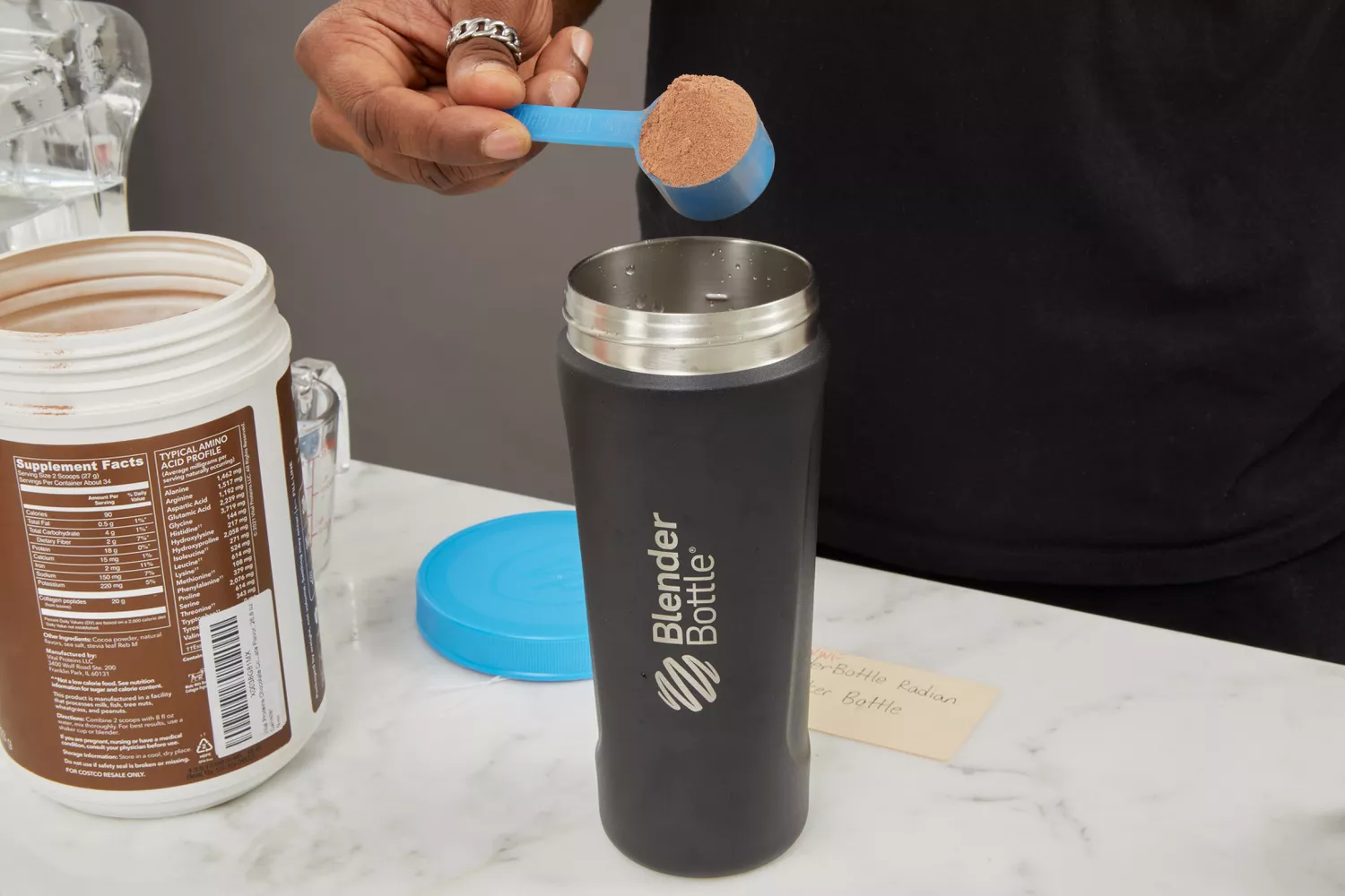Person holding scoop of protein powder over BlenderBottle Radian 26 oz Shaker Cup