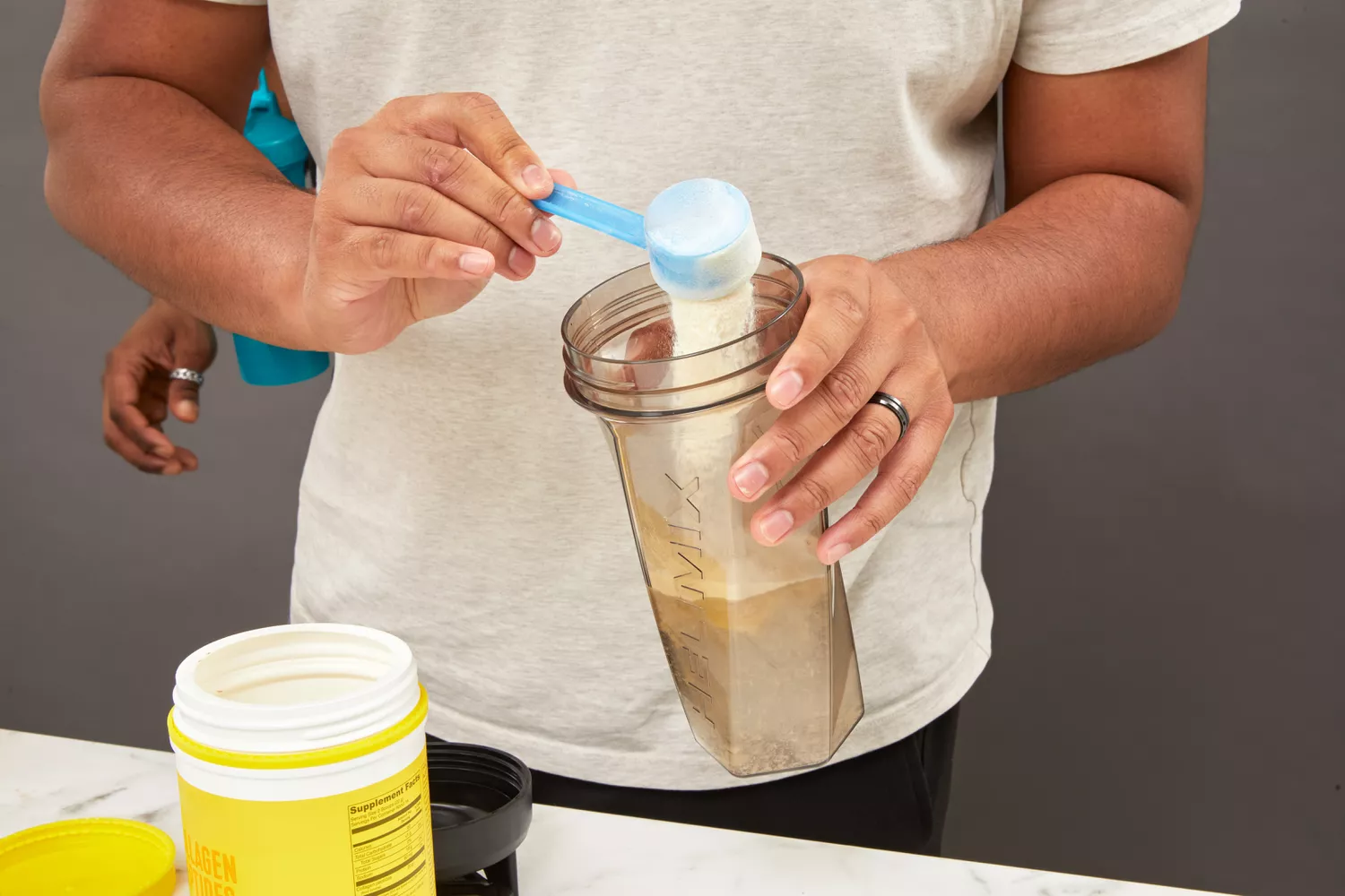 Person scooping powder into Helimix Vortex Blender Shaker Bottle
