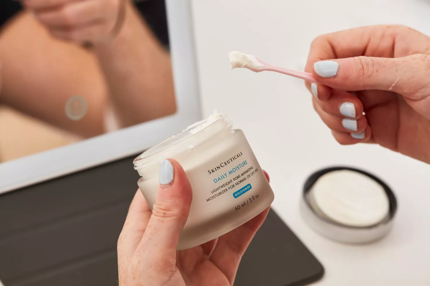 Hand scooping SkinCeuticals Daily Moisture with a small spatula