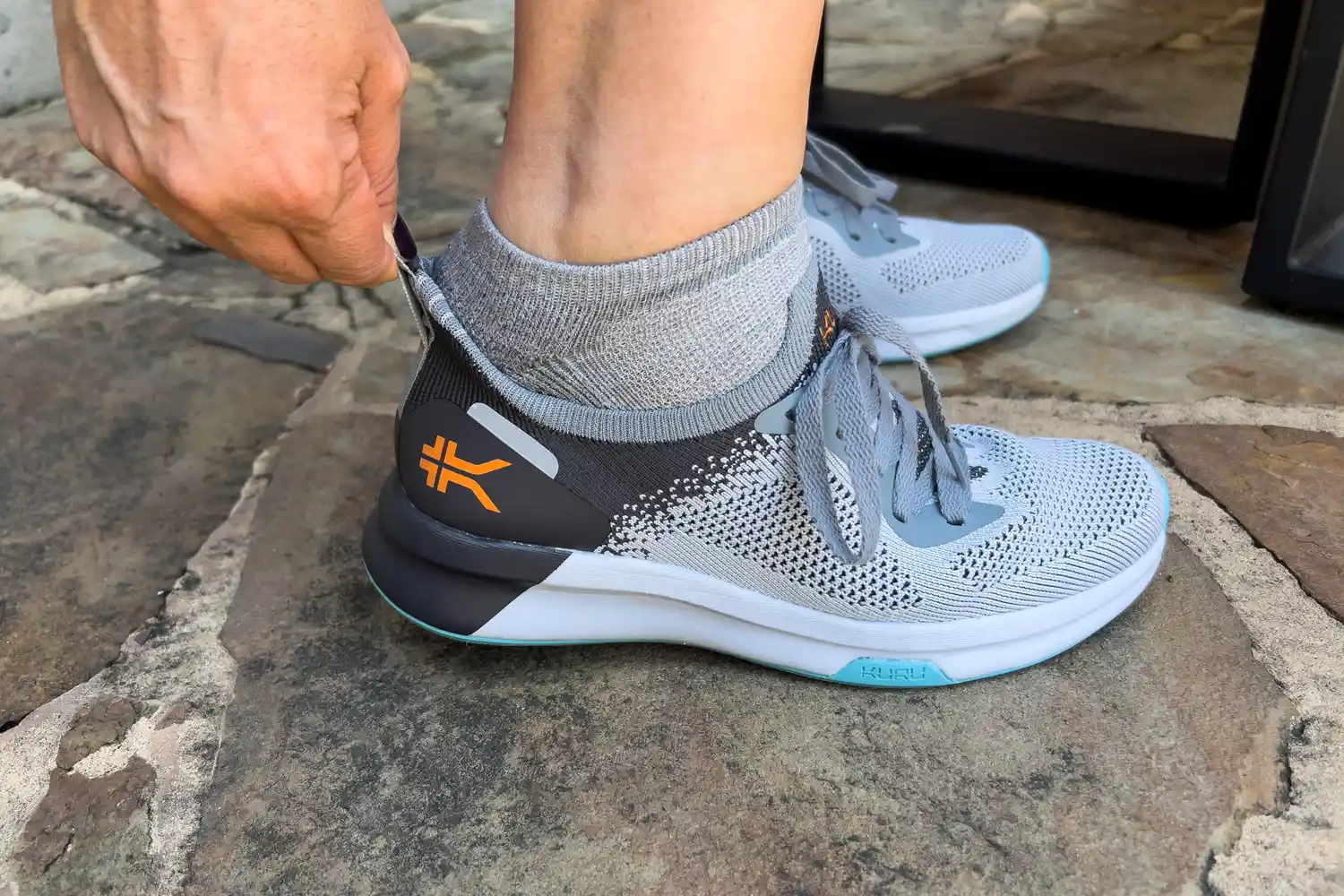 A person slips the Kuru Women's Flux Sneaker on while holding the heel 