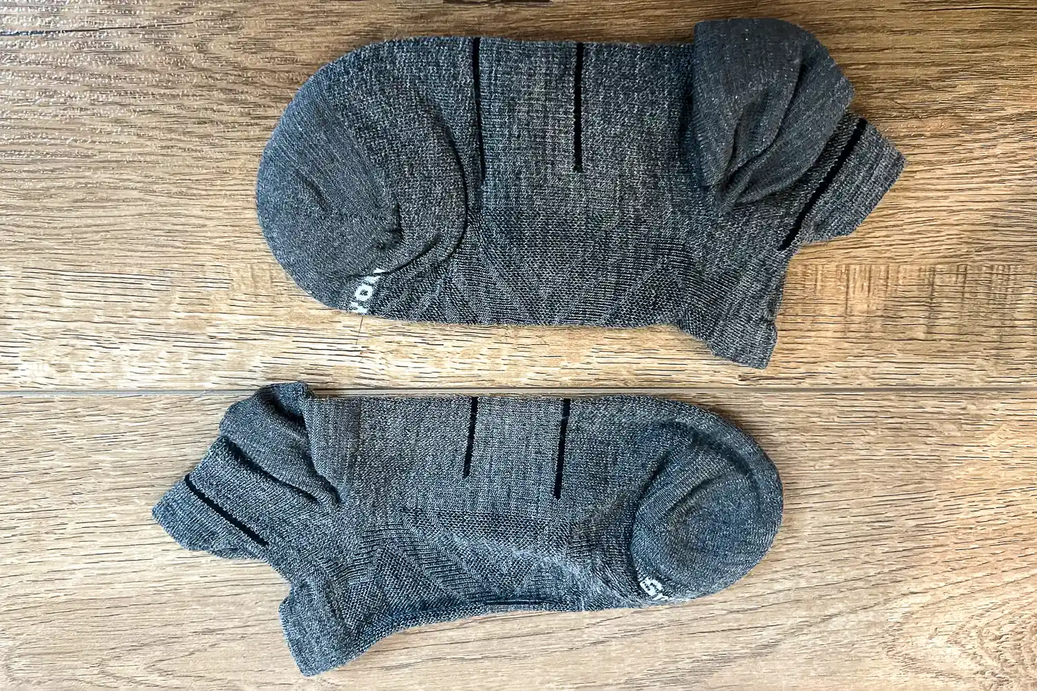 A pair of Smartwool Run Low Ankle Socks on a wooden floor