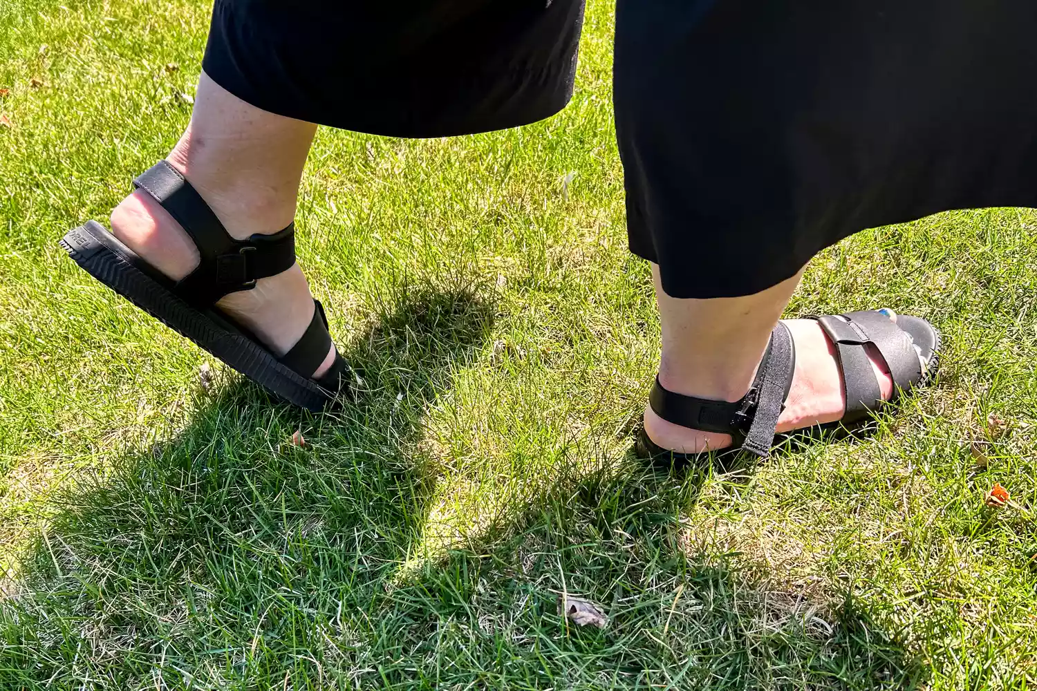 A close-up of feet wearing the Sorel ONA AVE Women's Ankle Strap Flat Sandal on grass
