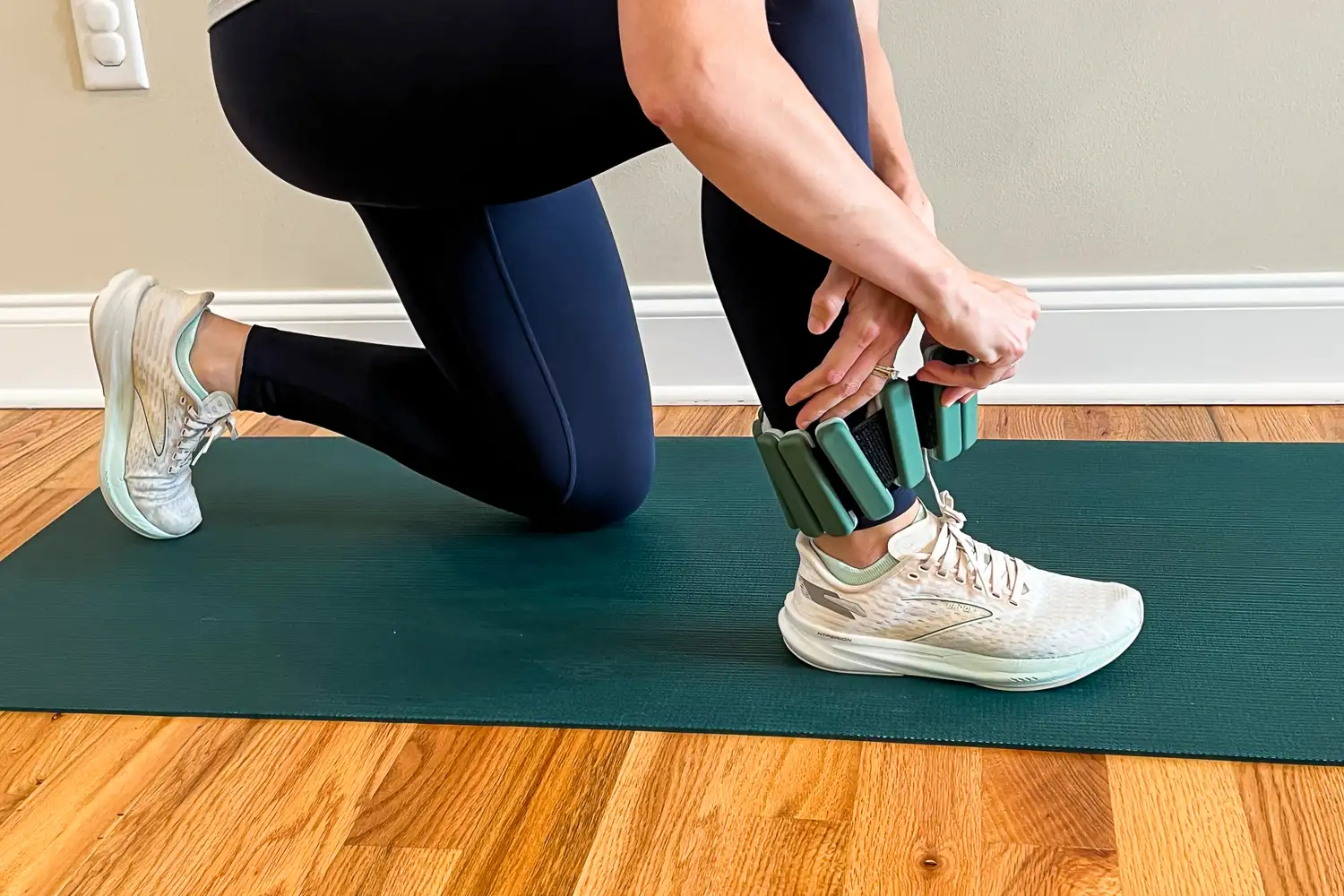 Person attaching Sportneer Ankle Weights while kneeling on a mat