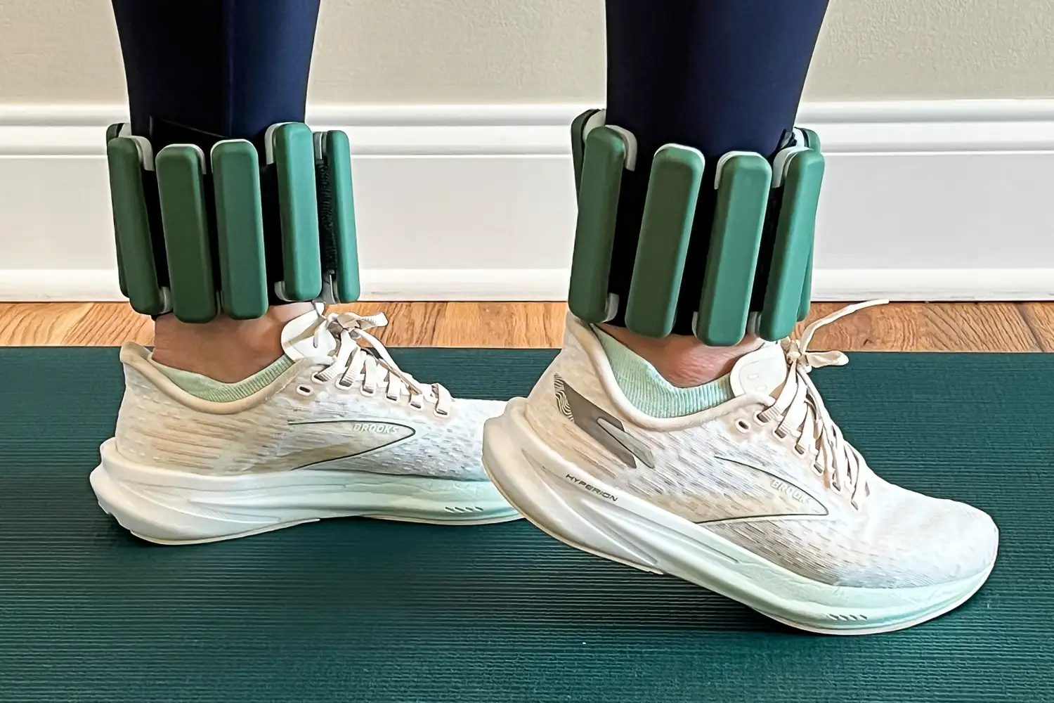Legs wearing Sportneer Ankle Weights and sneakers on a yoga mat