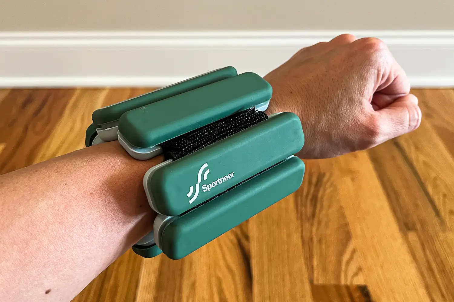 A closeup of a persons wrist wearing green Sportneer Weights
