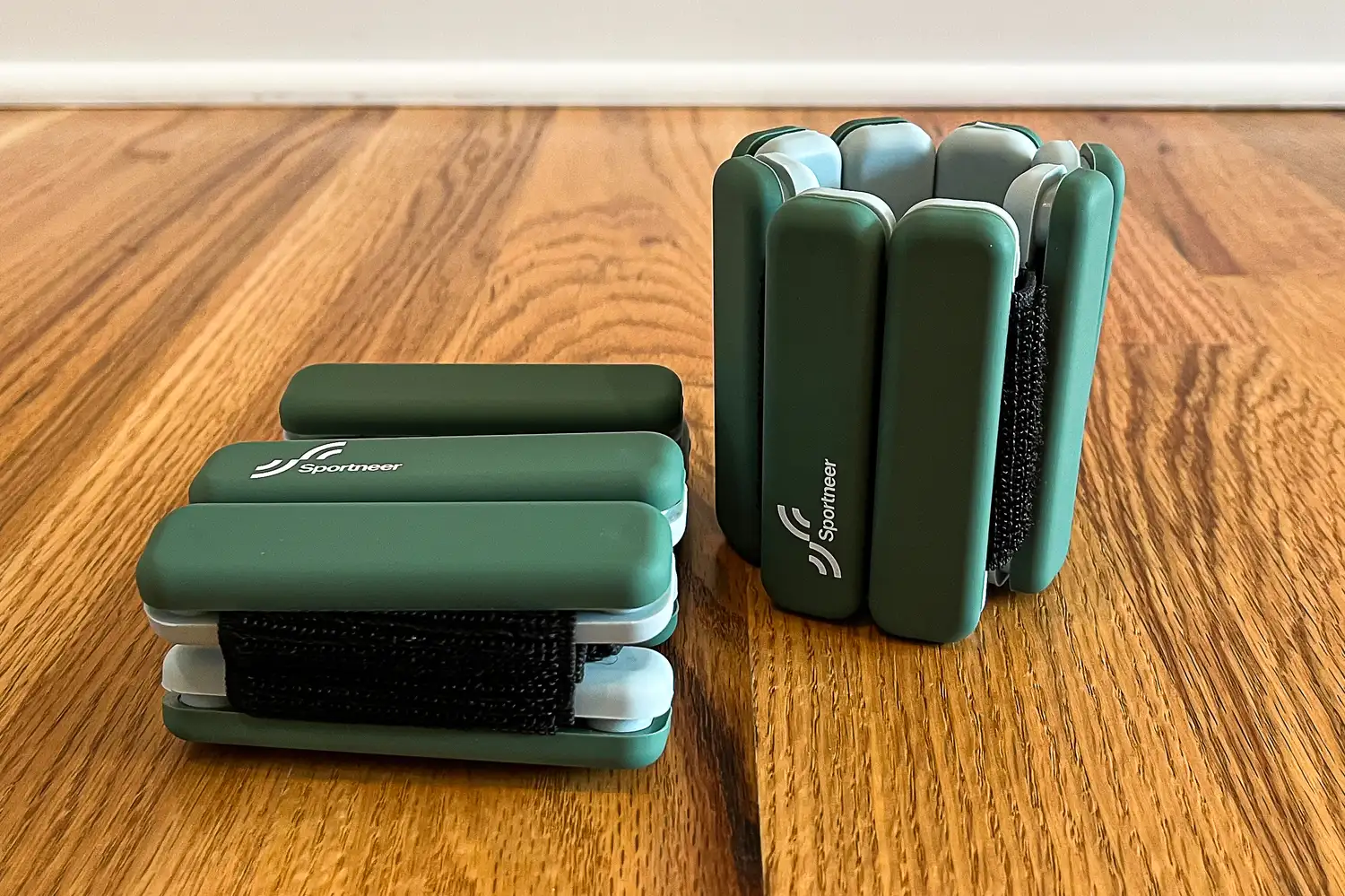 A pair of green Sportneer Wrist and Ankle Weights on a hardwood floor