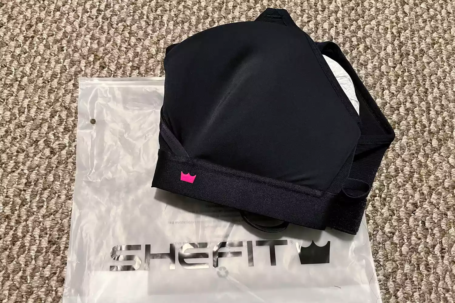 The SheFit Exhilarate Sports Bra on a carpeted floor