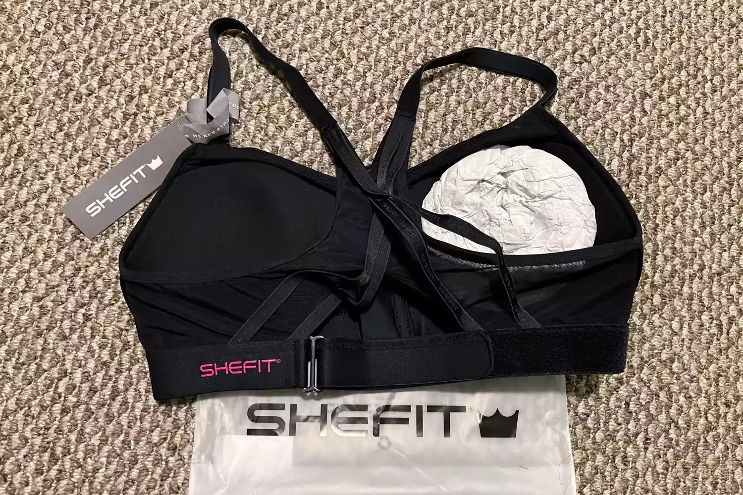 The SheFit Exhilarate Sports Bra on a carpeted floor