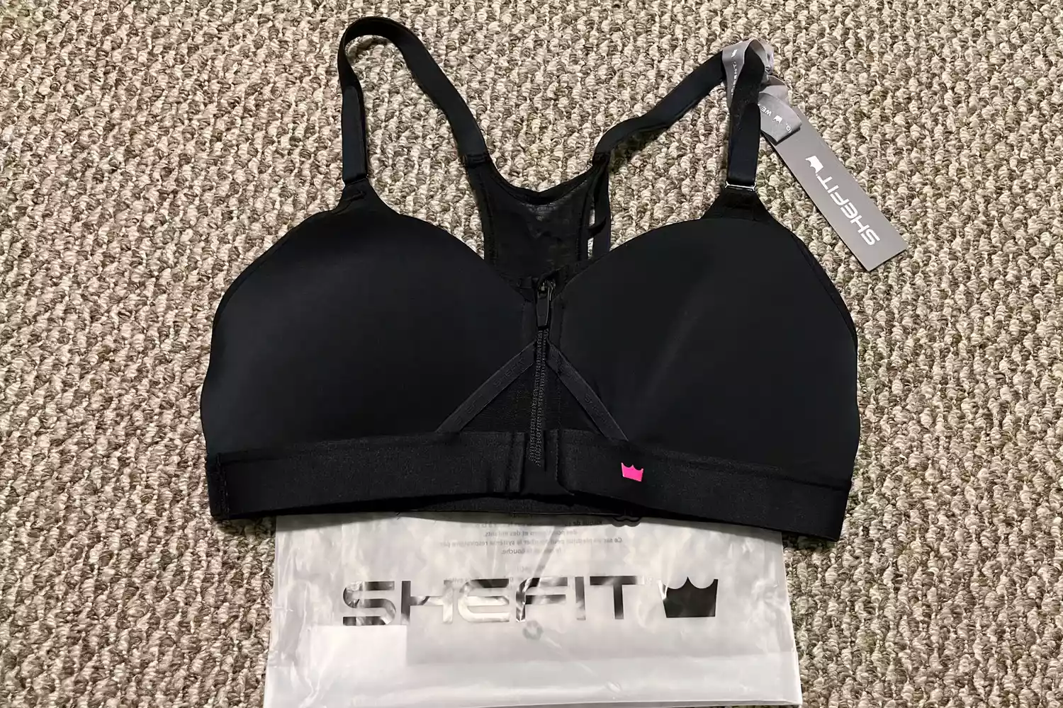 The SheFit Exhilarate Sports Bra on a carpeted floor