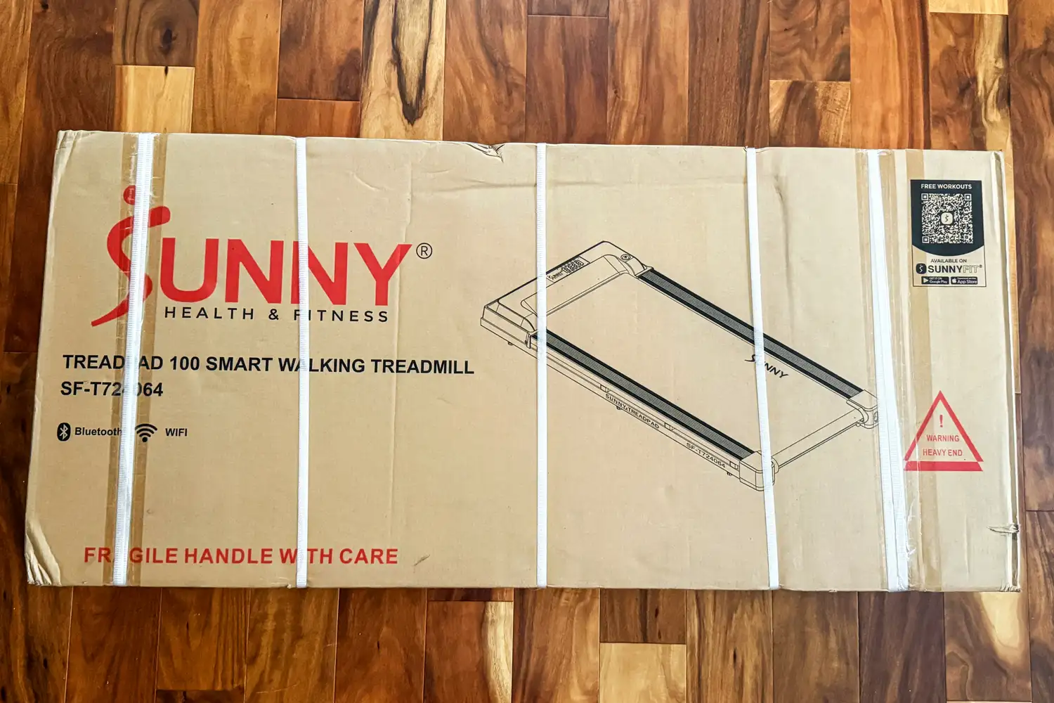 The Sunny Health & Fitness Treadpad 100 Smart Wi-Fi Connected Treadmill inside a cardboard shipping box