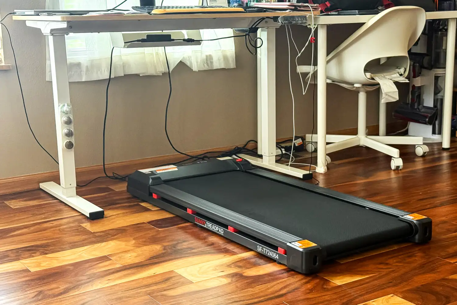 The Sunny Health & Fitness Treadpad 100 Smart Wi-Fi Connected Treadmill under a desk