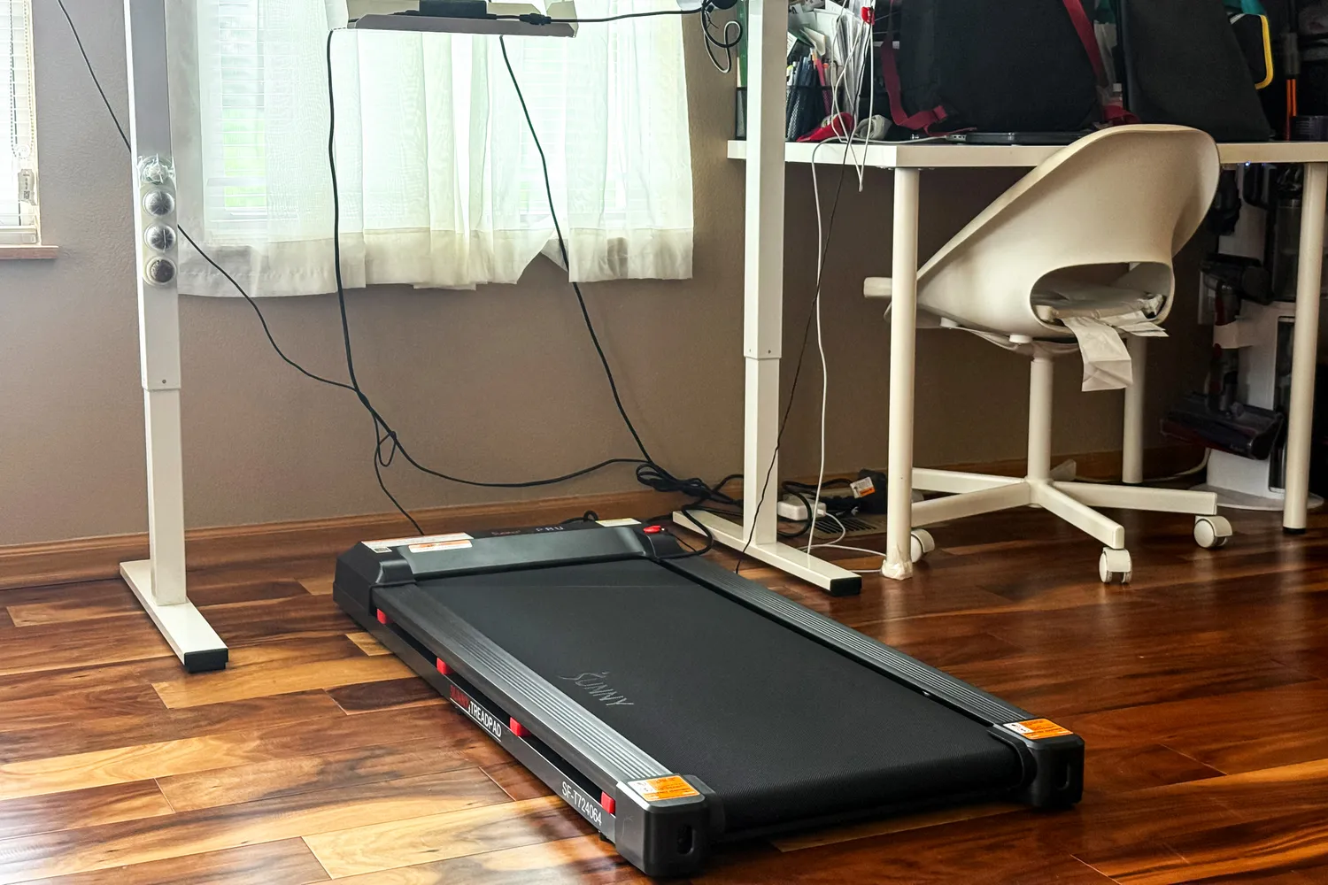 The Sunny Health & Fitness Treadpad 100 Smart Wi-Fi Connected Treadmill under a desk