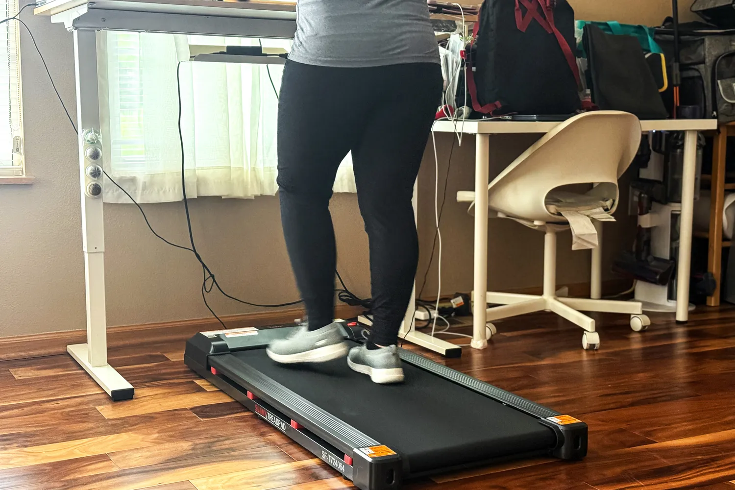A person walks on the Sunny Health & Fitness Treadpad 100 Smart Wi-Fi Connected Treadmill