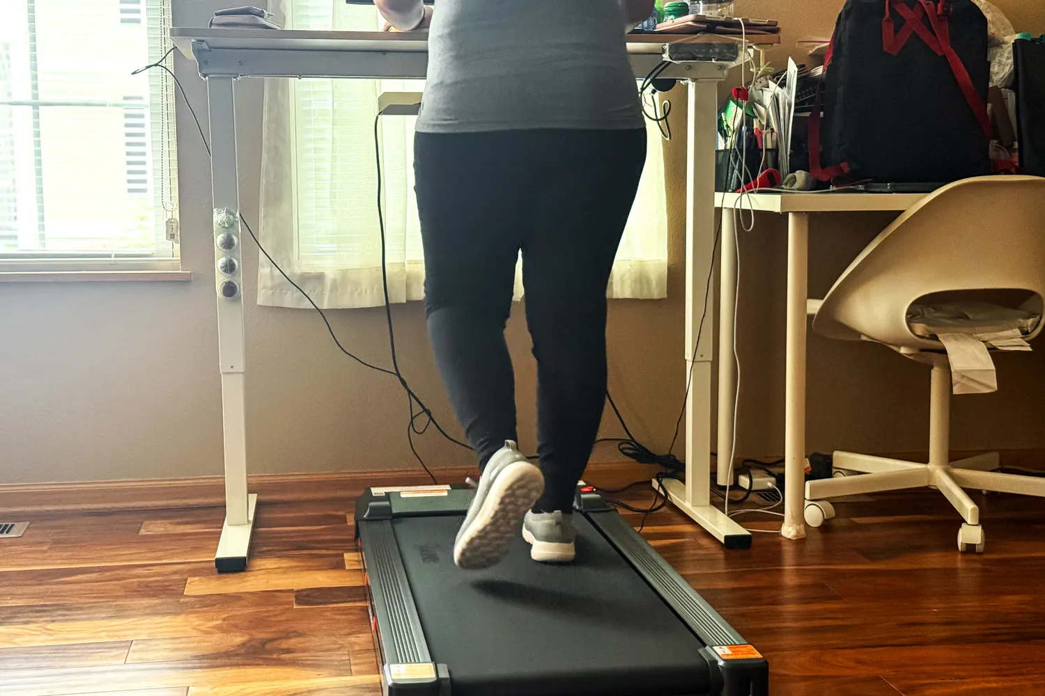 A person walks on the Sunny Health & Fitness Treadpad 100 Smart Wi-Fi Connected Treadmill