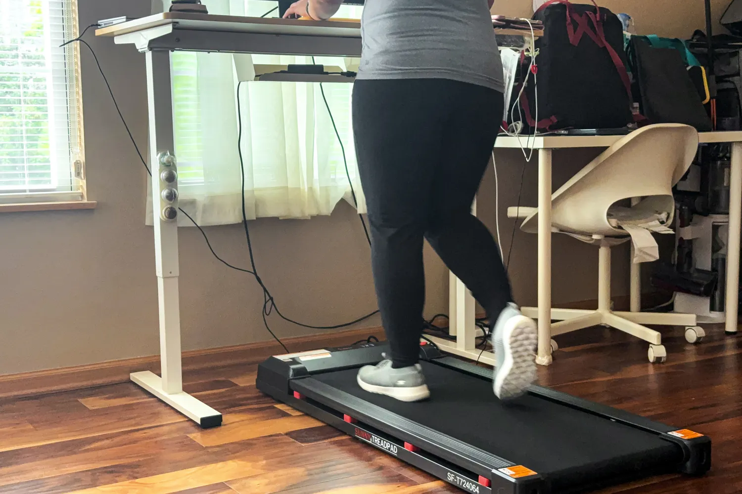 A person walks on the Sunny Health & Fitness Treadpad 100 Smart Wi-Fi Connected Treadmill