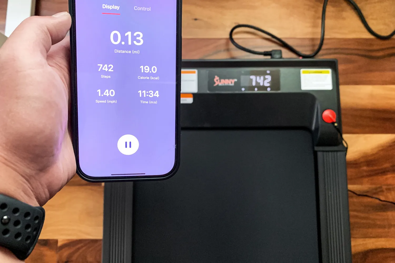 A person controls the Sunny Health & Fitness Treadpad 100 Smart Wi-Fi Connected Treadmill with a smartphone app