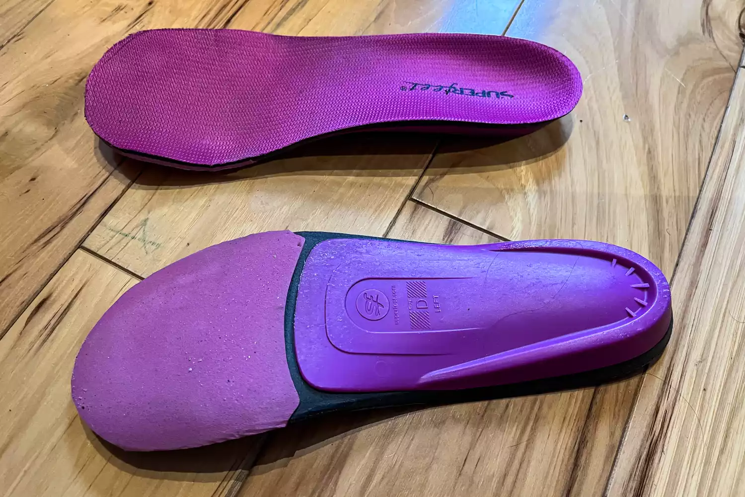 The Superfeet All-Purpose Women's High Impact Support Insoles on a wooden floor