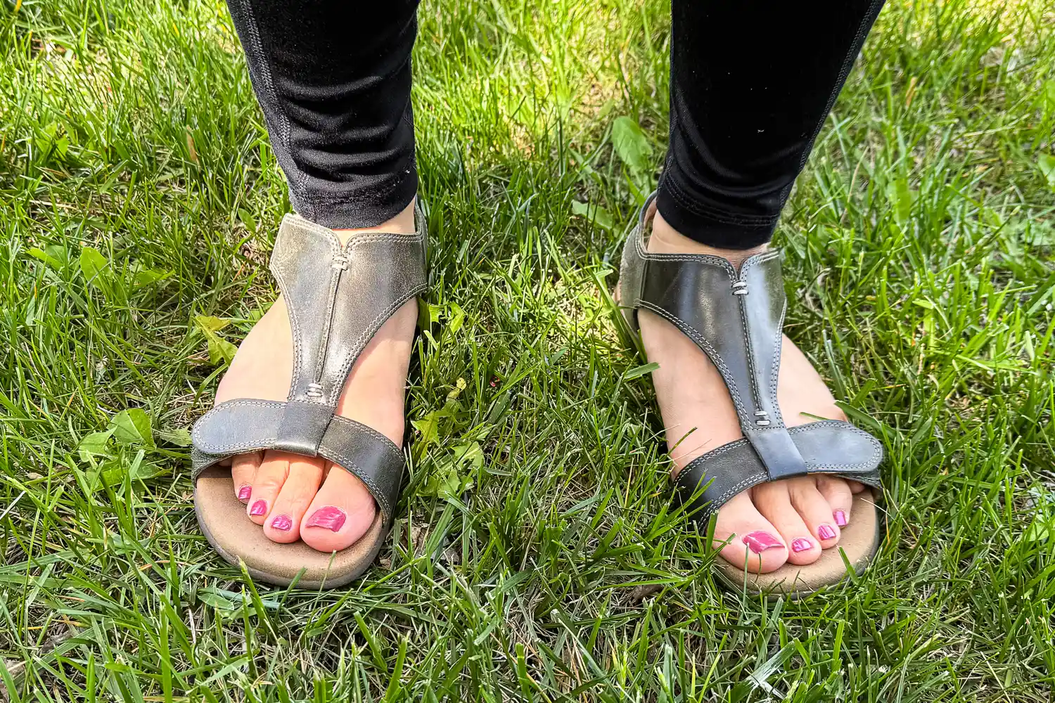 A person wears the Taos Women's The Show Sandals while standing in grass