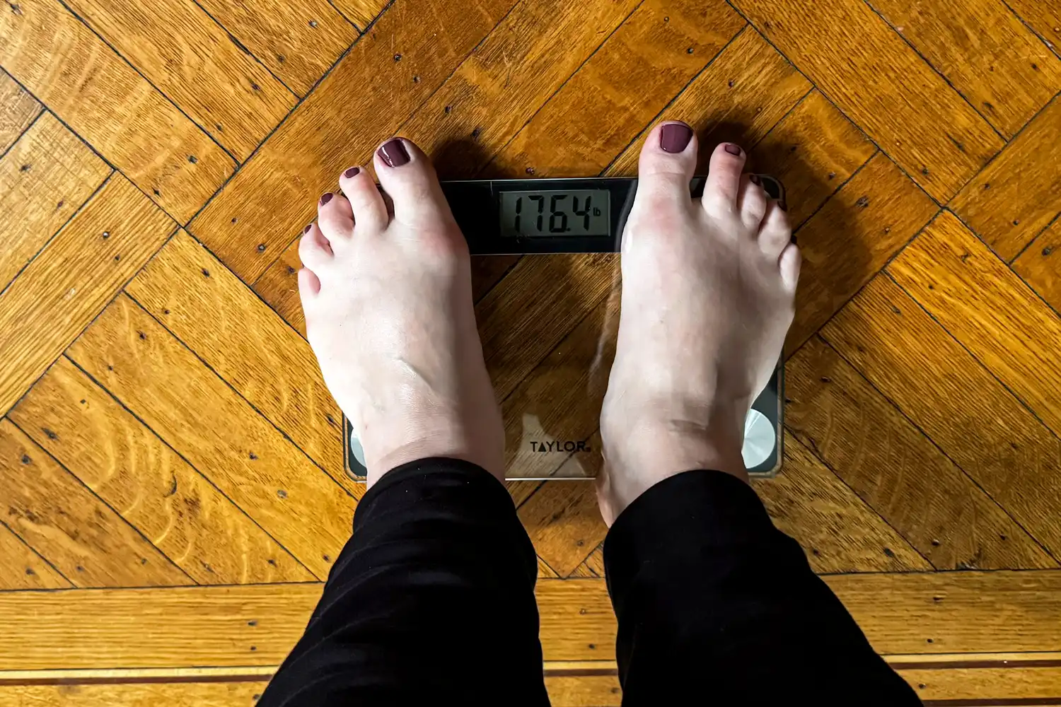 A person stands on the Taylor Digital Compact Scale with Travel/Storage Tote barefoot