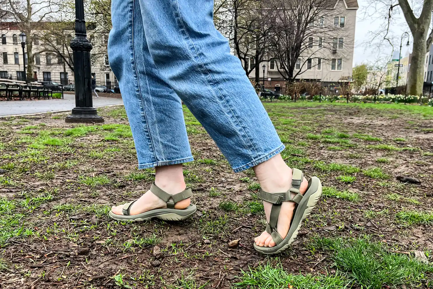 A close-up of legs walking on grass and dirt while wearing the Teva Women's Hurricane XLT2