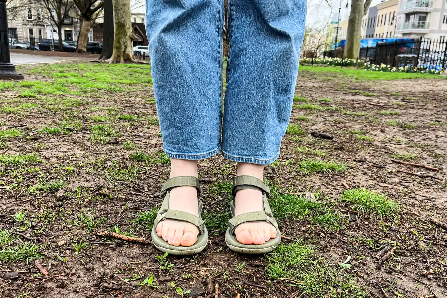 Two legs wearing the Teva Women's Hurricane XLT2 sandals on dirt