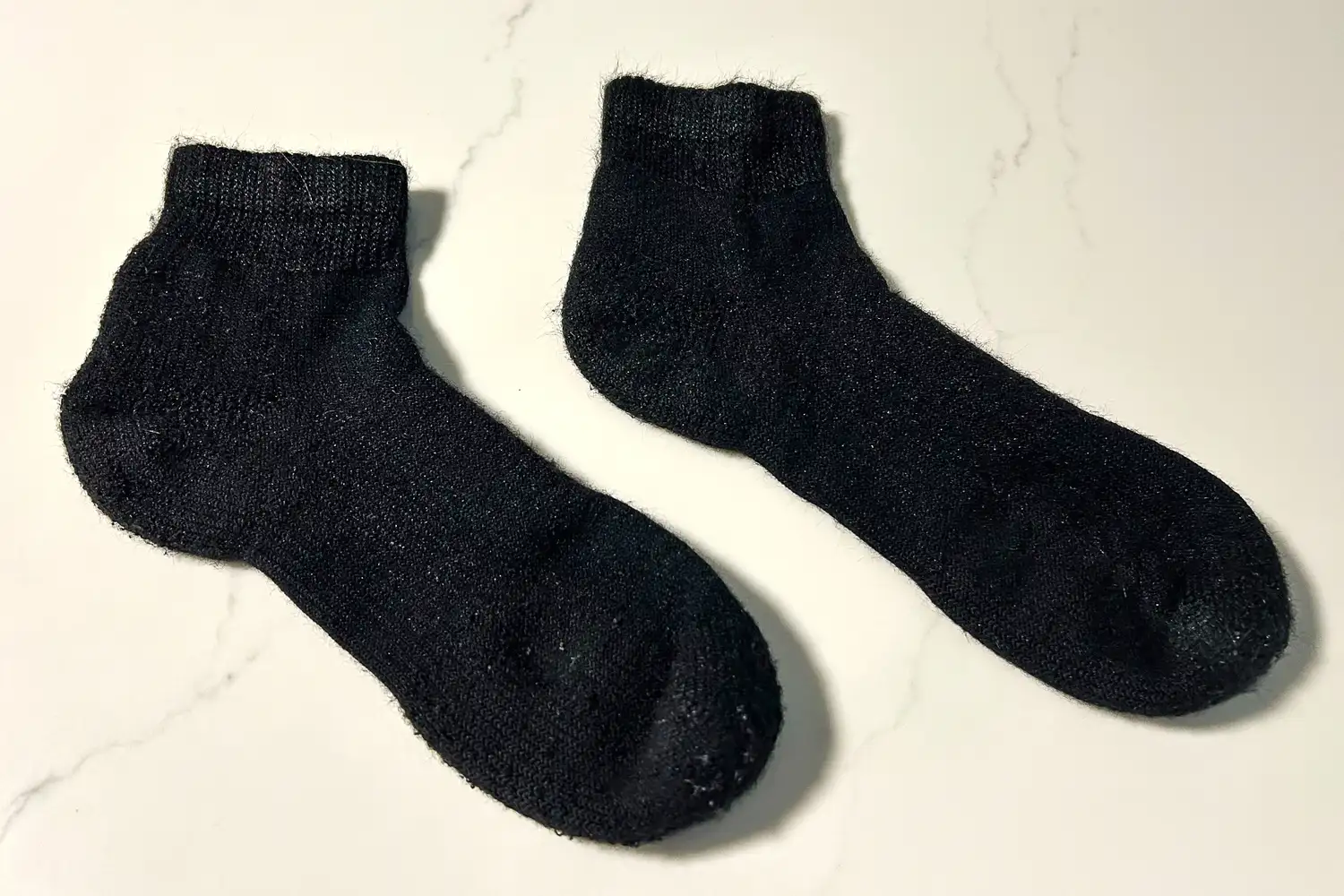 A pair of Thorlo WMX Moderate Cushion Ankle Walking Socks on a marble countertop