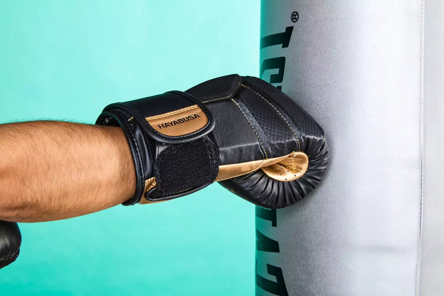 A person hitting a heavy bag while wearing Hayabusa T3 Boxing Gloves
