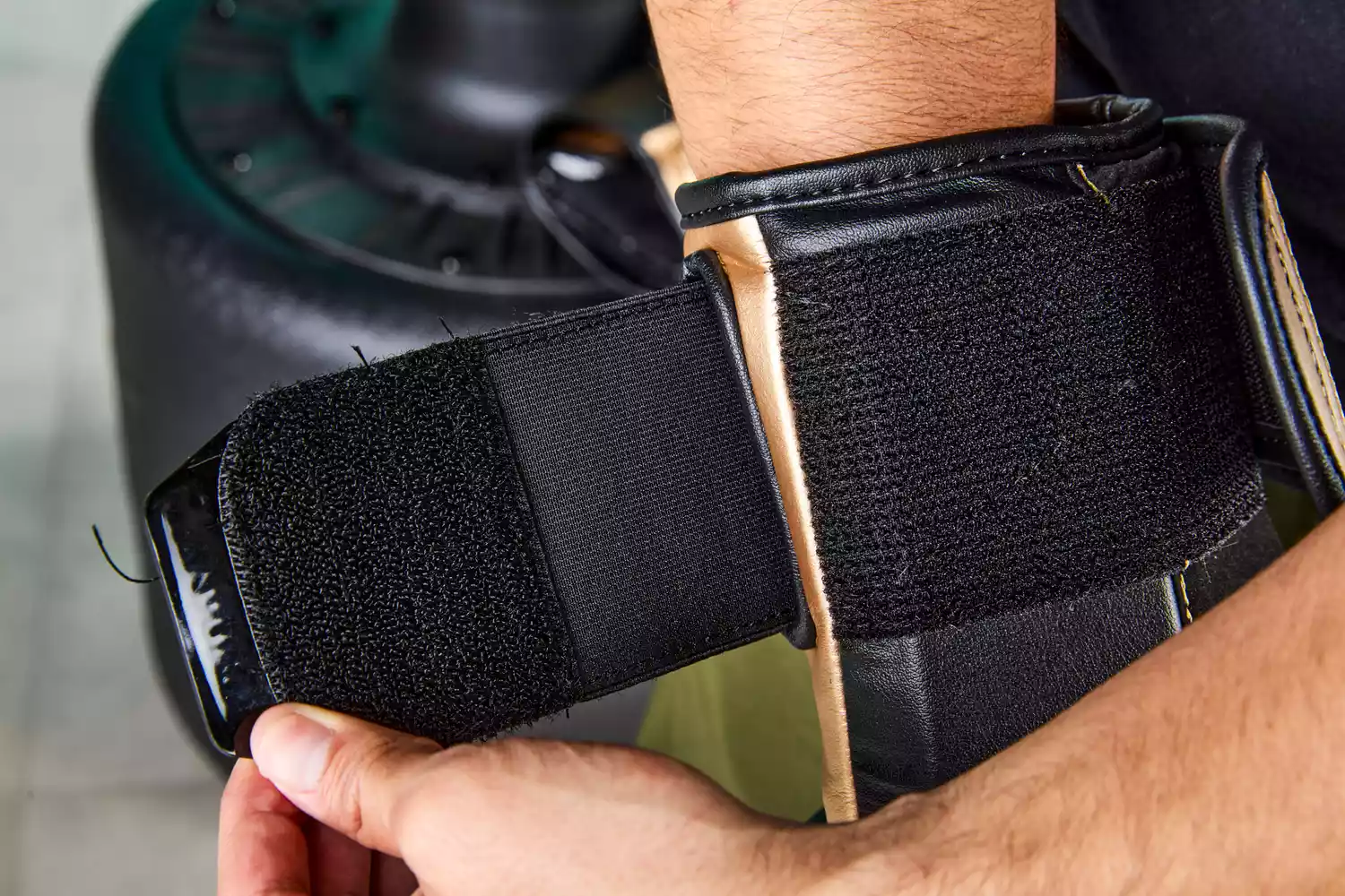 A person opening the velcro strap on Hayabusa T3 Boxing Gloves