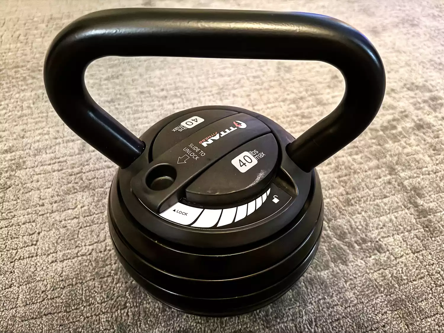 The Titan Fitness 40 lb Adjustable Kettlebell on a carpet
