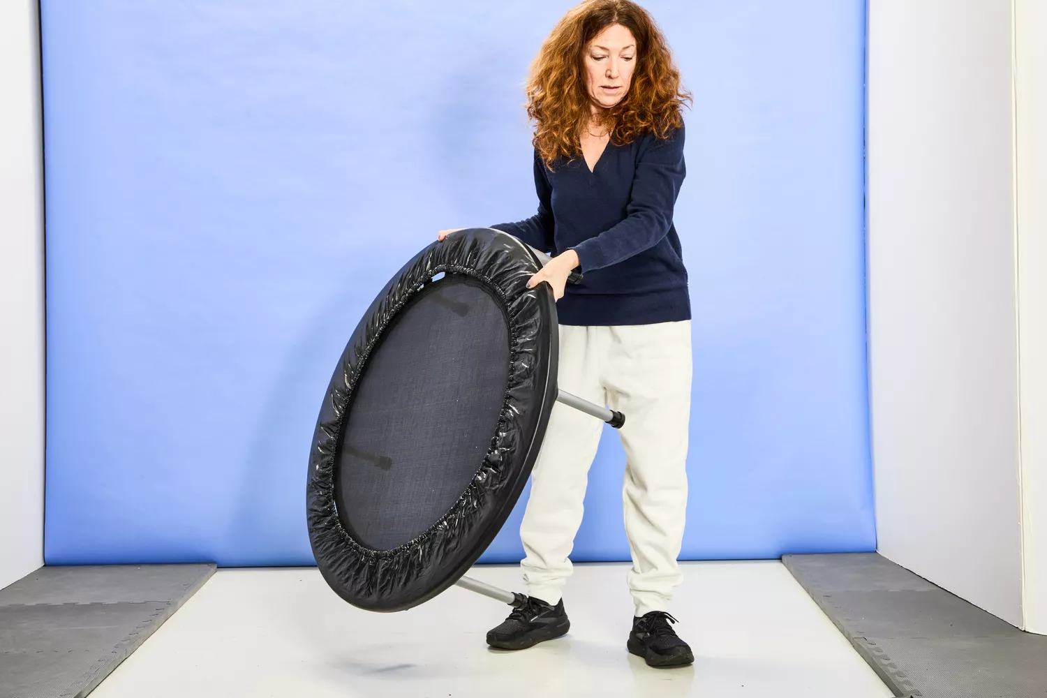 A person lifting the Fitness Gear Mini Trampoline in the air
