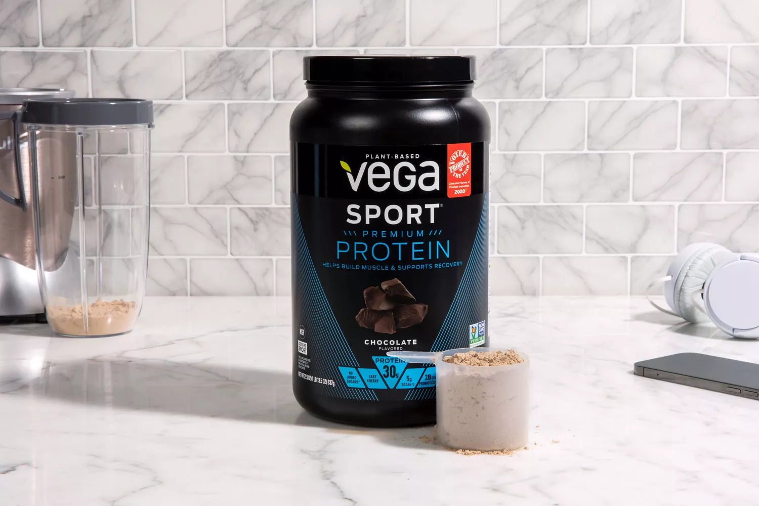 Vega Sport Premium Protein on marble counter next to scoop of protein powder