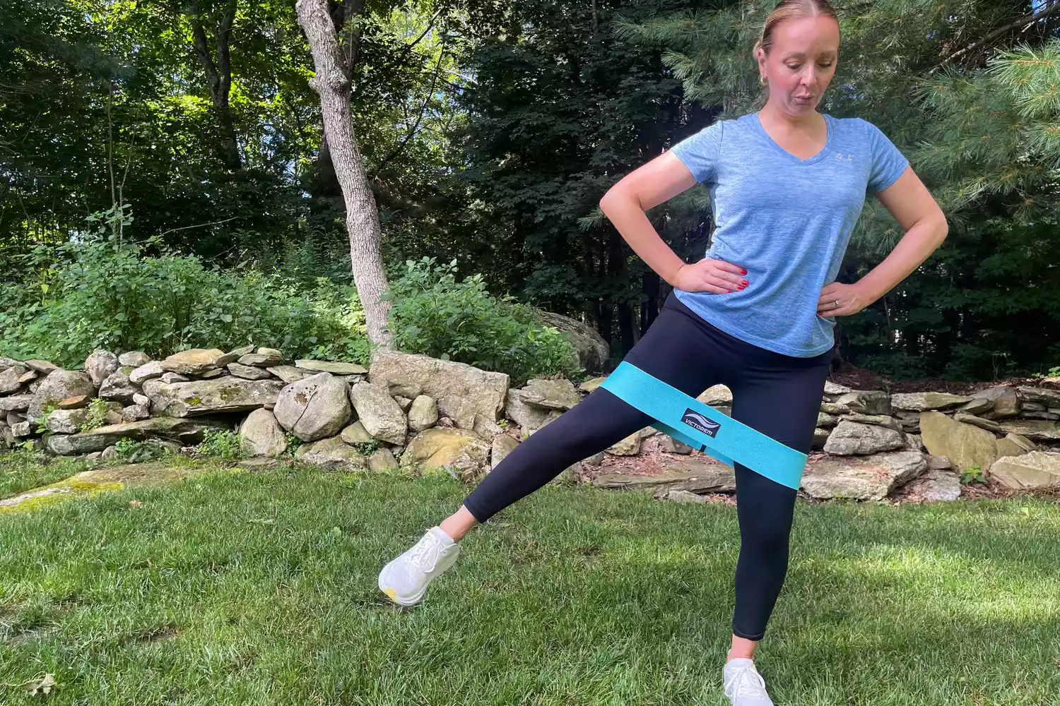 A person exercising on grass while wearing the teal Victorem Resistance Hip Booty Band on their thighs