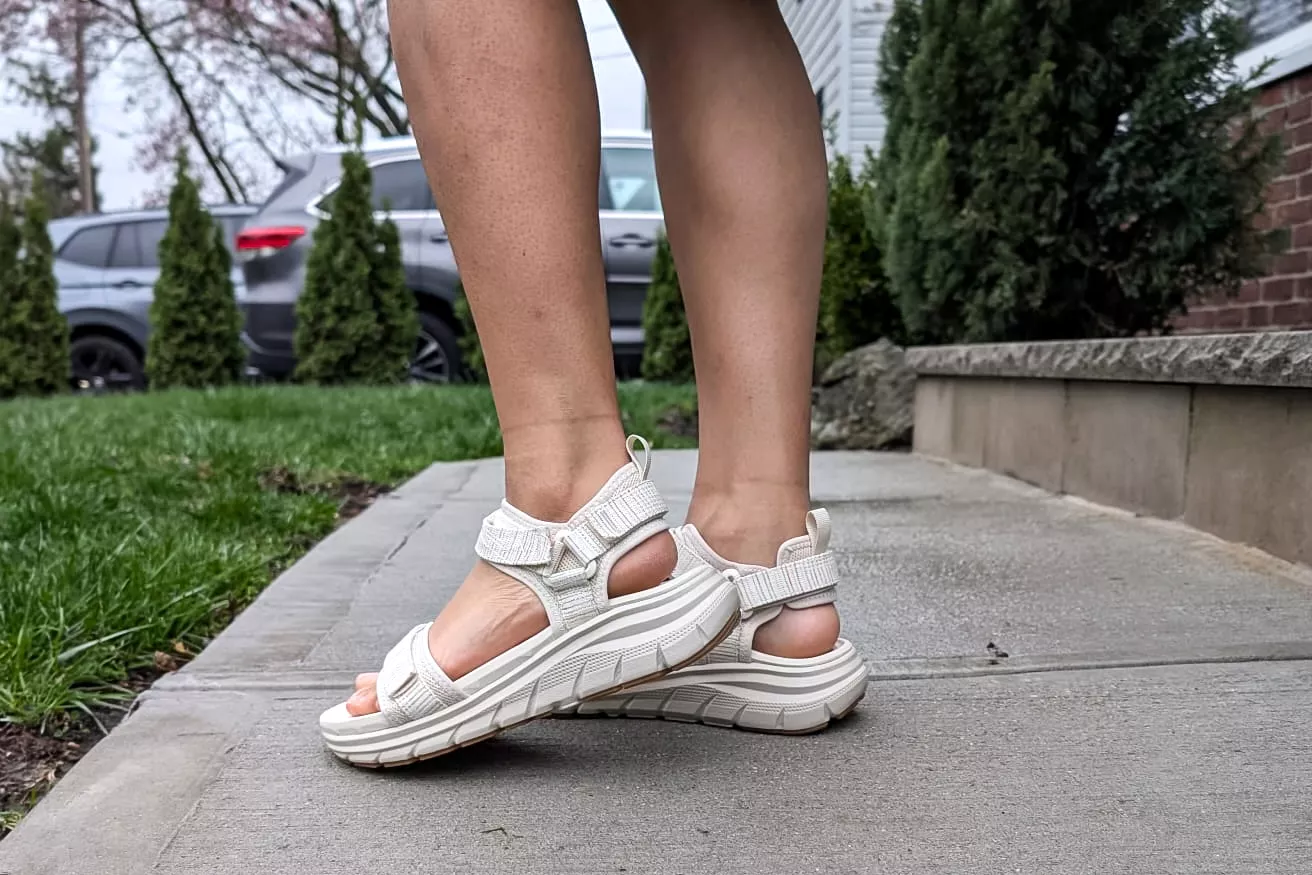 A close-up of legs wearing the Vionic Walk Max Wanderer Sandals on concrete