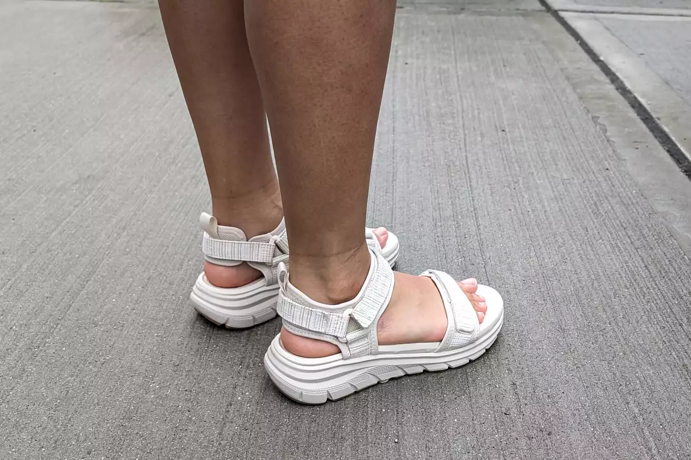 Feet on concrete while wearing the Vionic Walk Max Wanderer Sandal