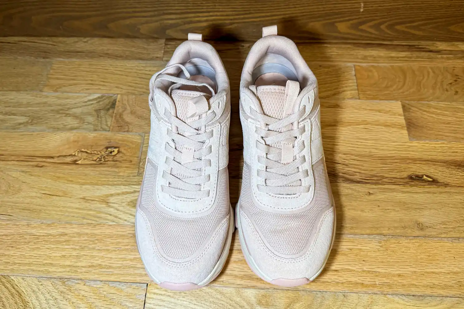 A pair of Vionic Women's Walk Strider Sneakers on a wooden floor