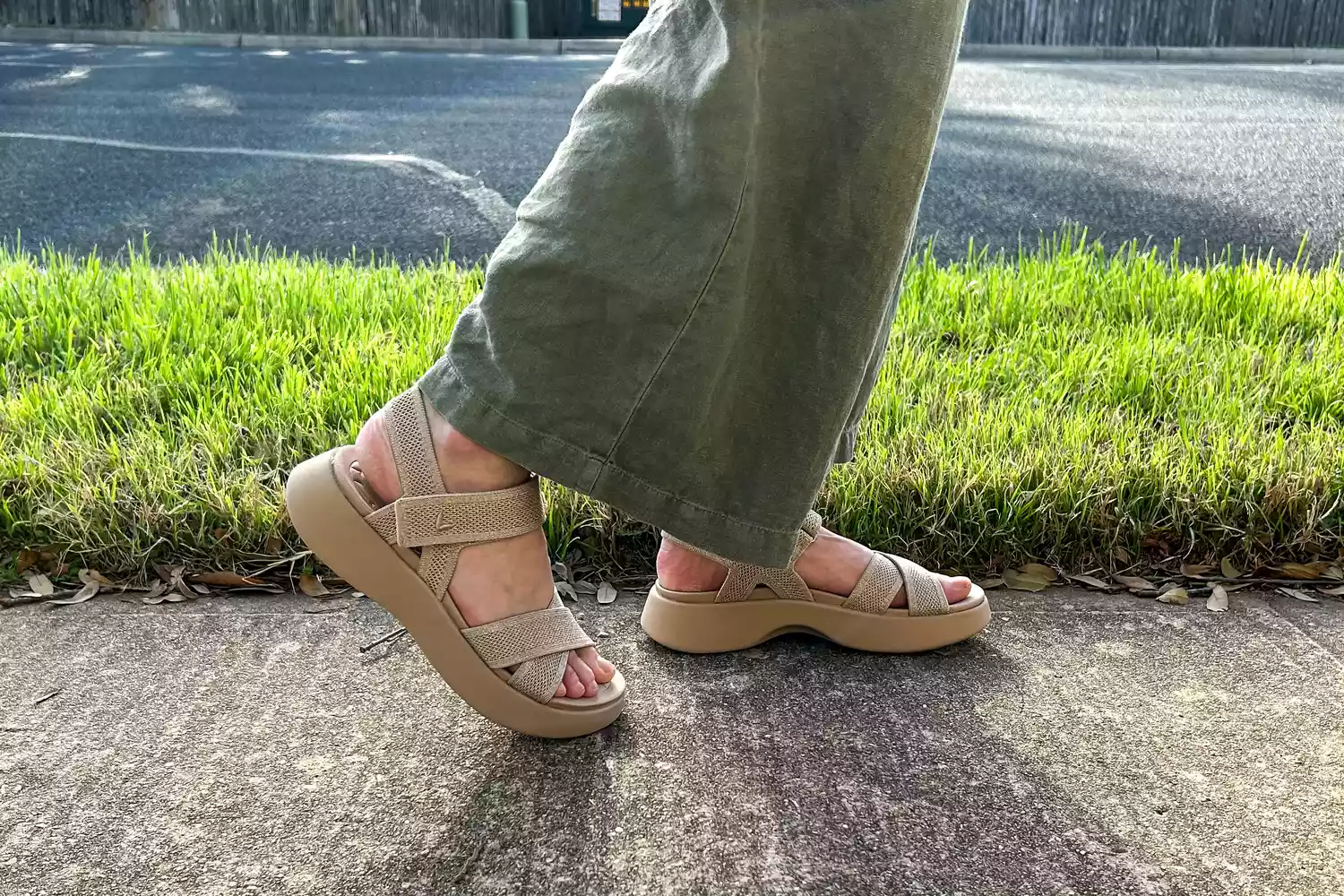 A close-up of legs to the side while wearing the Vivaia Kiara Sport Sandals on concrete