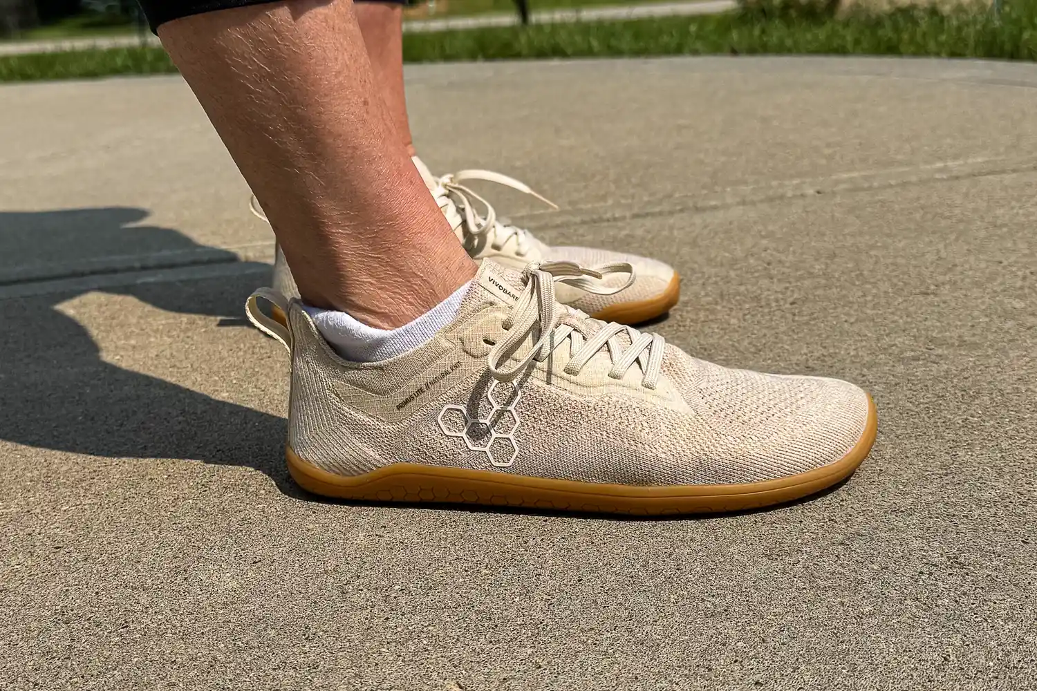 A side view of a person wearing the Vivobarefoot Women's Primus Lite Knit Natural Sneakers
