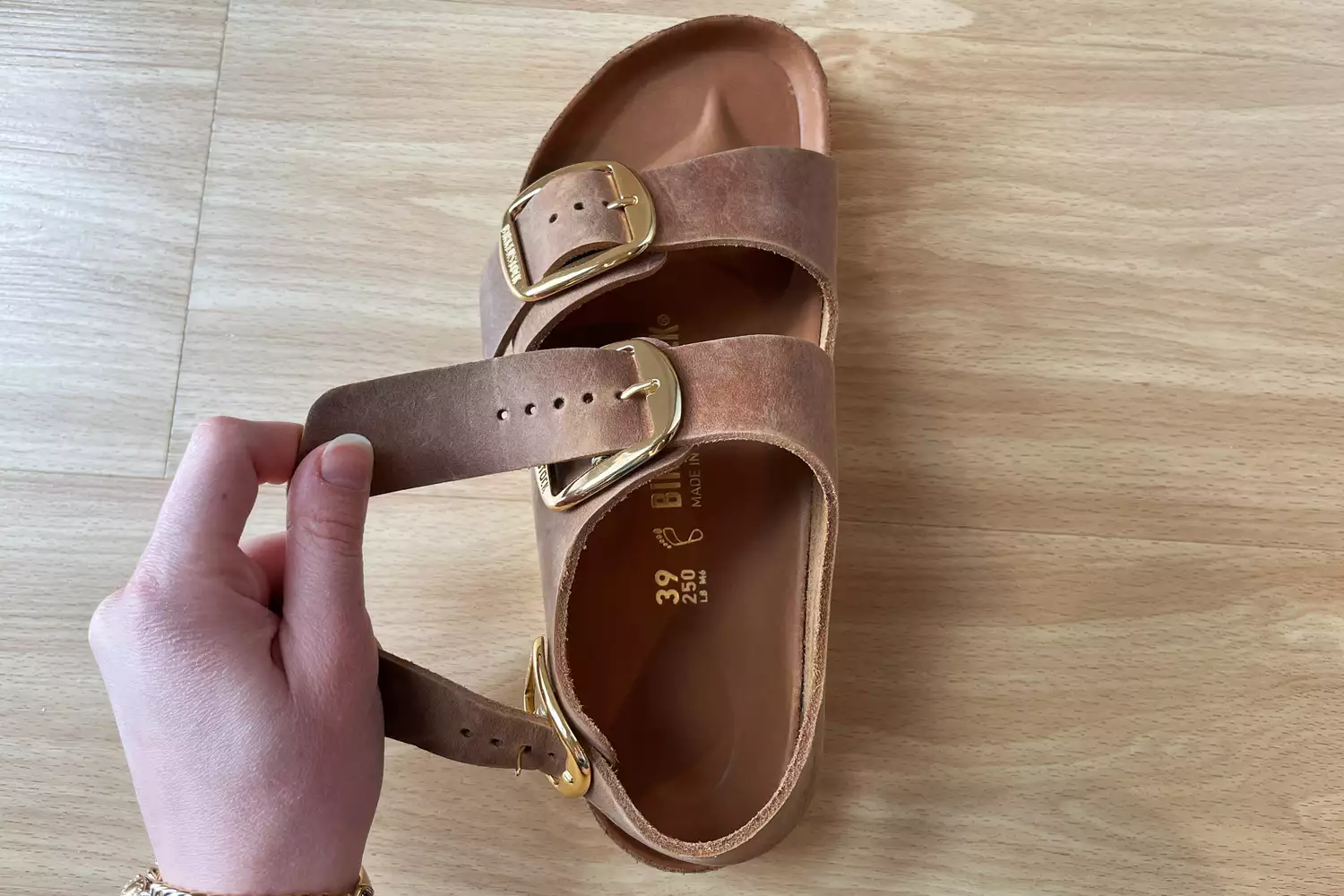 Hand holding a buckle strap on a Birkenstock Milano Big Buckle Sandal