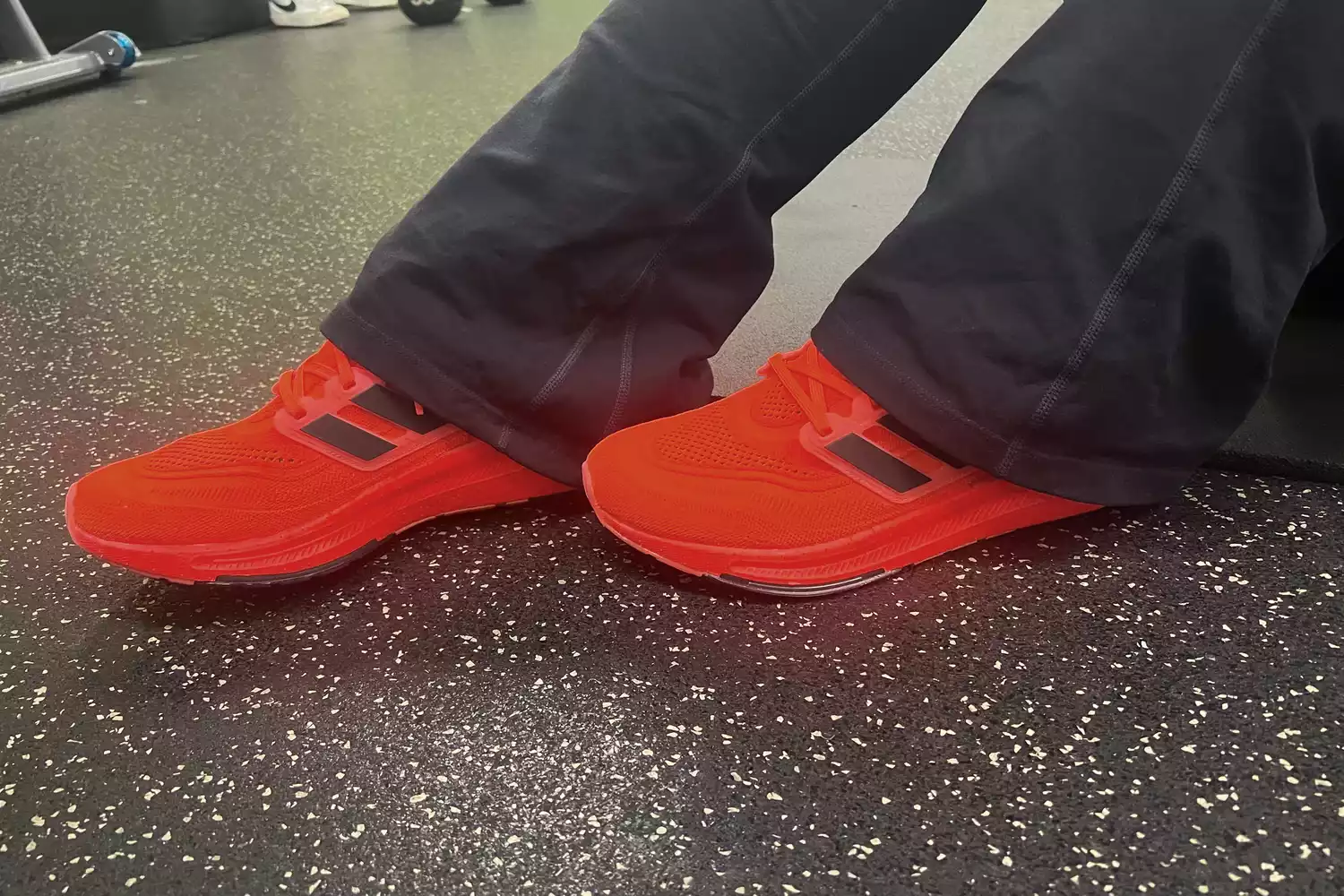 Feet wearing Adidas Ultraboost on black surface