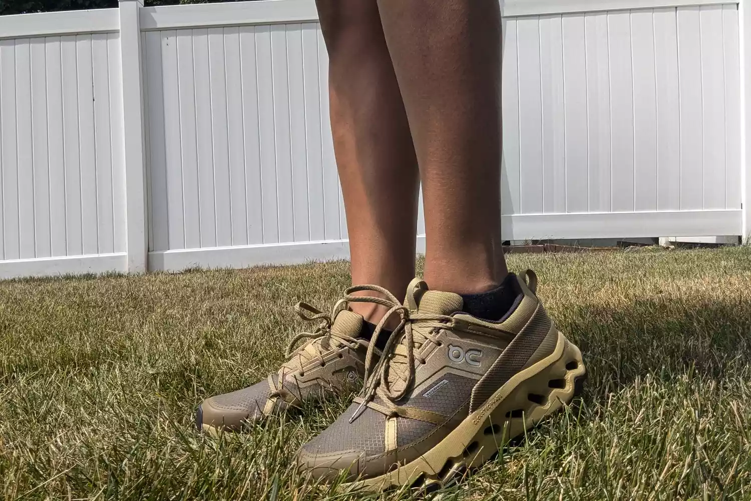 A person stands in grass while wearing the On Running Women's Cloudhorizon Waterproof Running Shoes