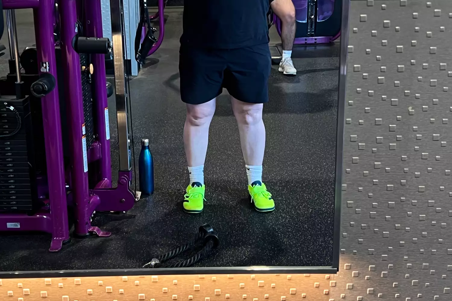 A person wears the adidas The Total Shoes Unisex Weightlifting Sneakers while working out at the gym