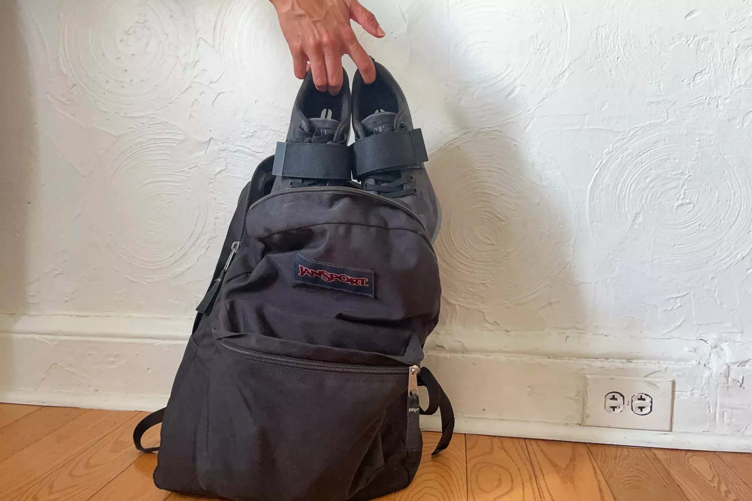 A person places the NOBULL Women's Canvas Lifter Shoes into a backpack