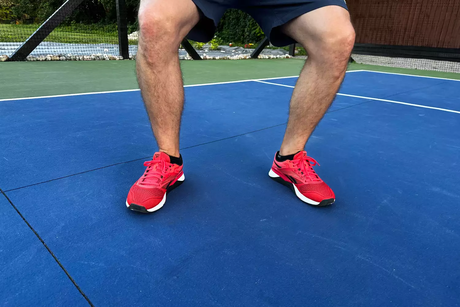 A person squats while wearing the Reebok Unisex Nano X4 Training Shoes